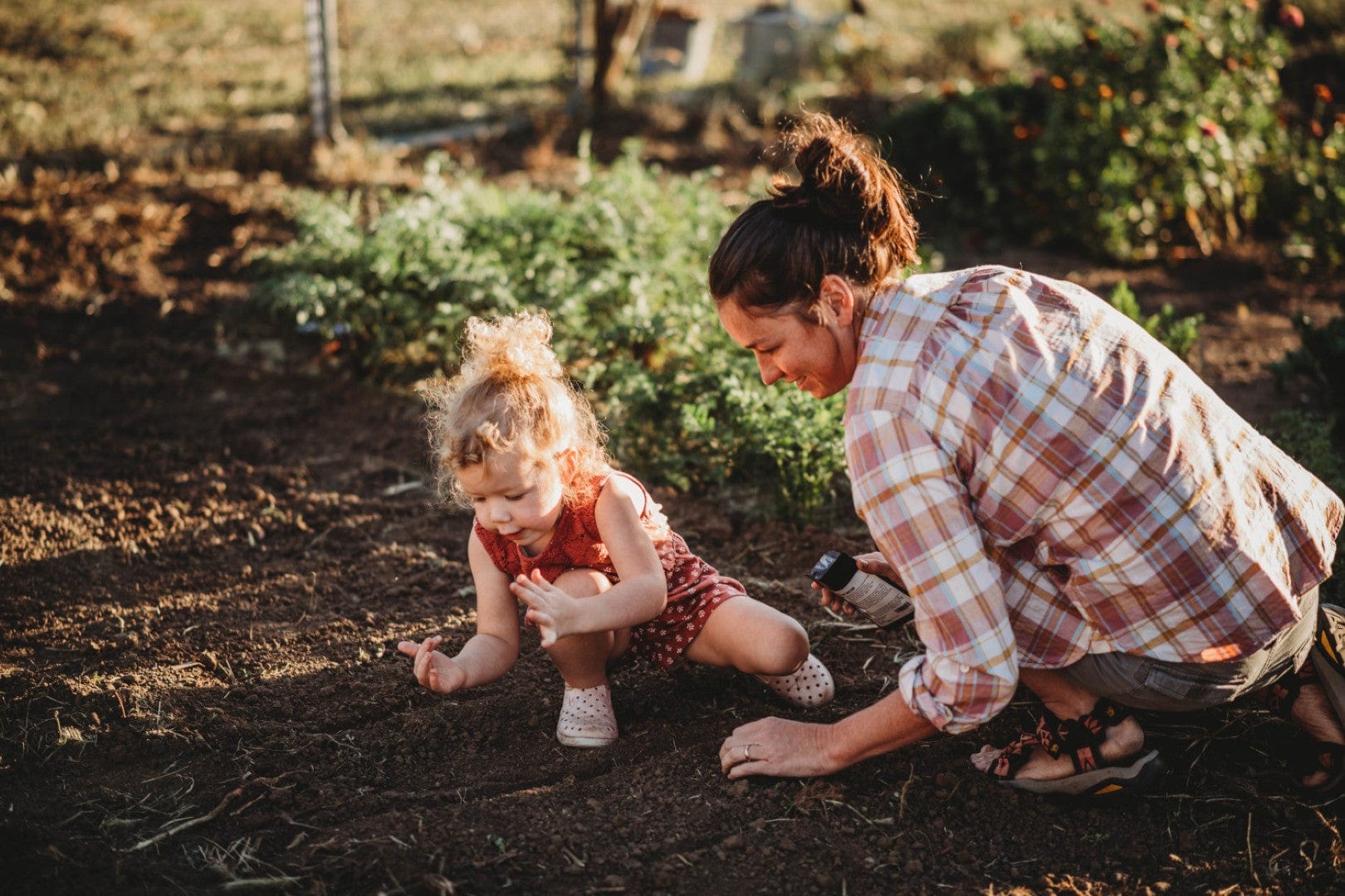 mother and daughter planting into raised garden bedbed