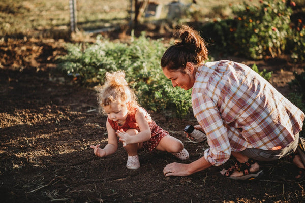 mother and daughter planting into raised garden bedbed
